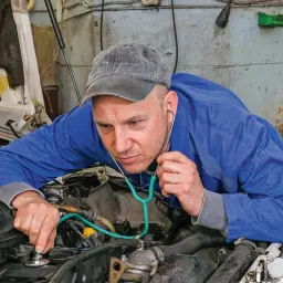 Mechanik z wyspecjalizowanym stetoskopem nasłuchuje pracy silnika, sprawdzając, czy tłoki działają prawidłowo.