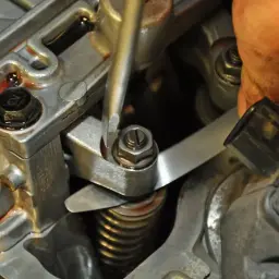 Mechanik reguluje zawory w silniku, używając śrubokręta i cienkiego metalowego narzędzia.