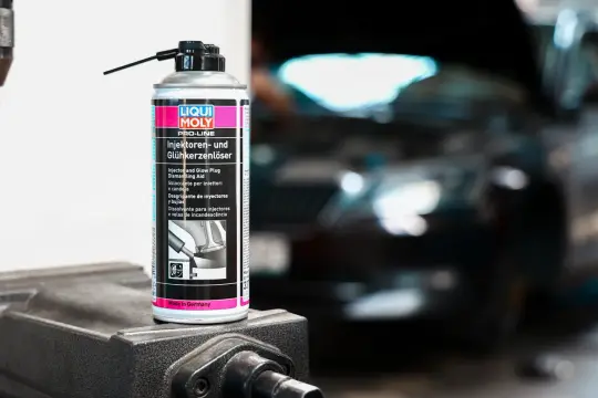 Puszka preparatu Liqui Moly do czyszczenia wtryskiwaczy i świec żarowych na tle rozmazanego silnika.