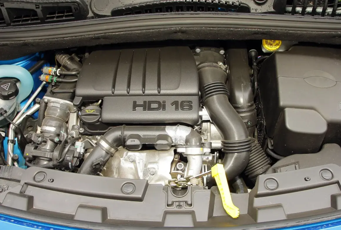 Silnik HDI 16 w Peugeot 307. Widoczny jest czarny plastikowy kolektor dolotowy i inne elementy pod maską.