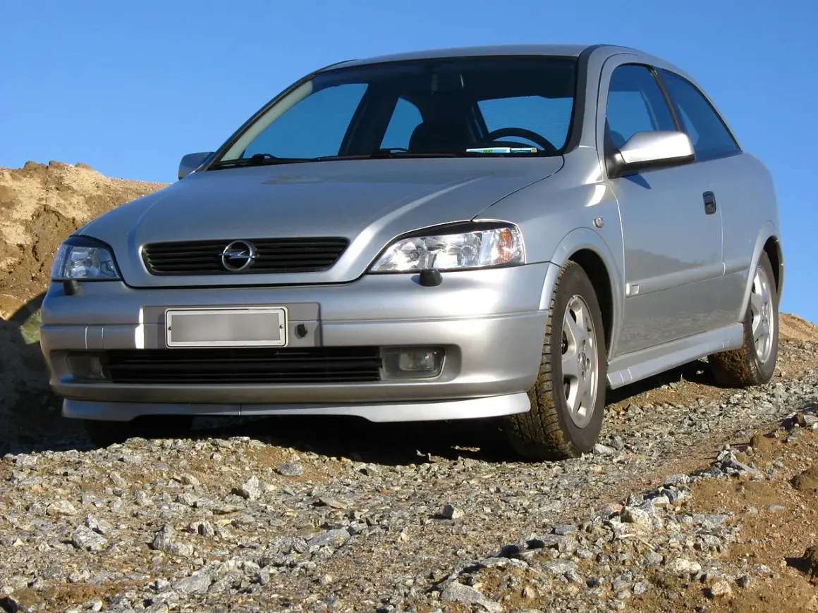 Srebrny Opel Astra G 1.6 16v na kamienistym podjeździe, gotowy na przygodę.