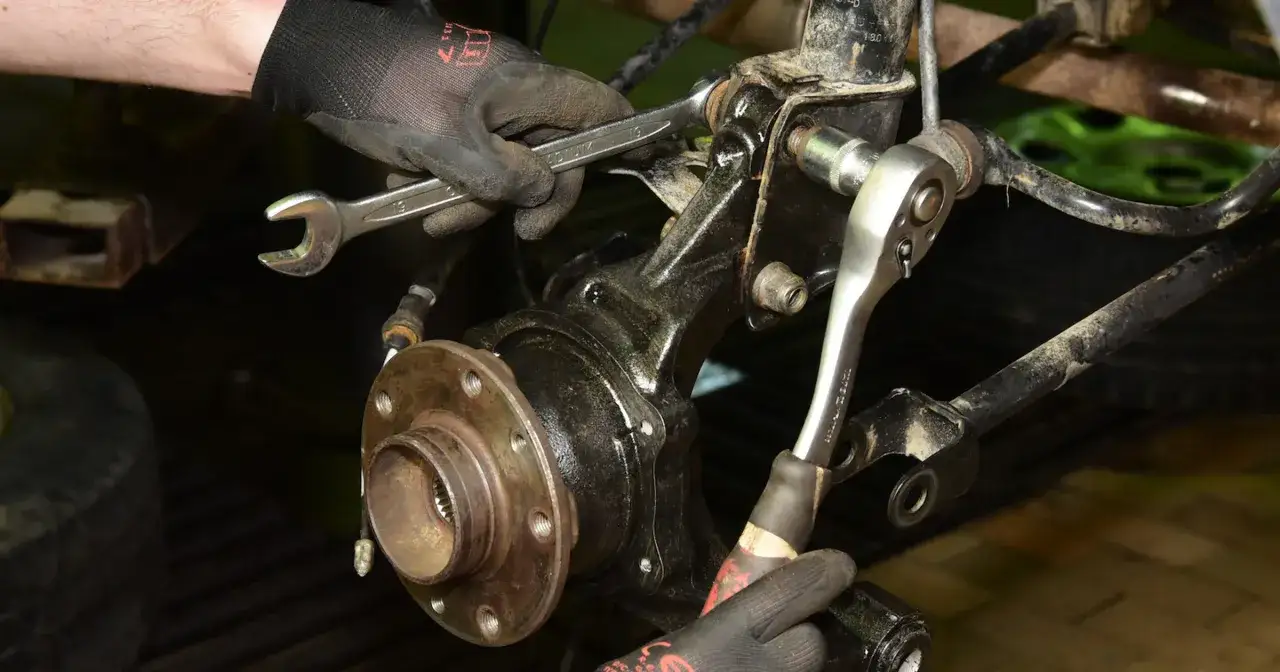 Mechanik dokręca śruby przy piaście koła. Huczące łożysko jak długo można jeździć? Czas na wymianę!