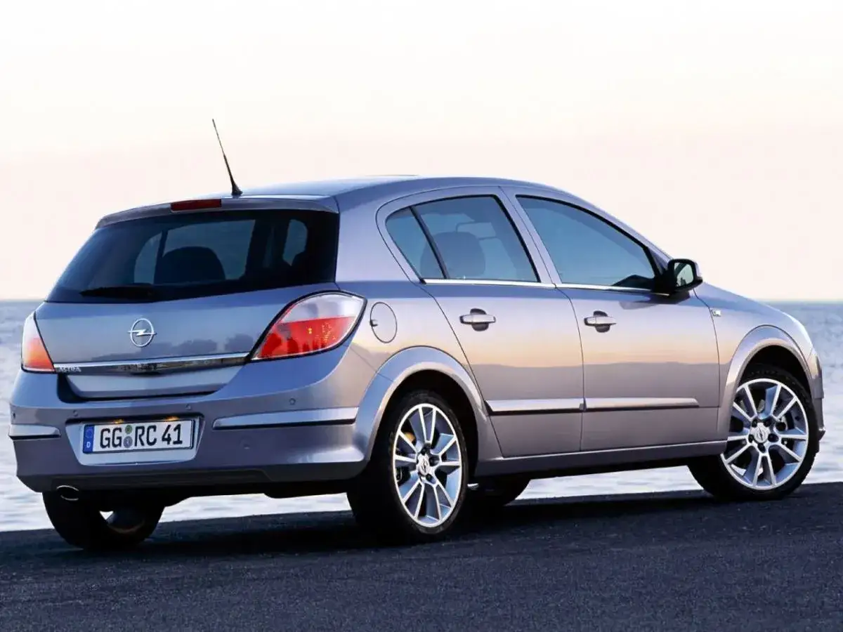 Srebrny Opel Astra H 1.6 benzyna z widocznym tyłem, zaparkowany nad morzem.
