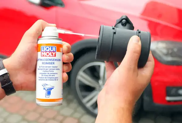 Czyszczenie przepływomierza preparatem Liqui Moly. W tle czerwony samochód.