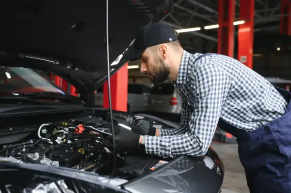 Mechanik w warsztacie sprawdza stan cewek zapłonowych w silniku samochodu.
